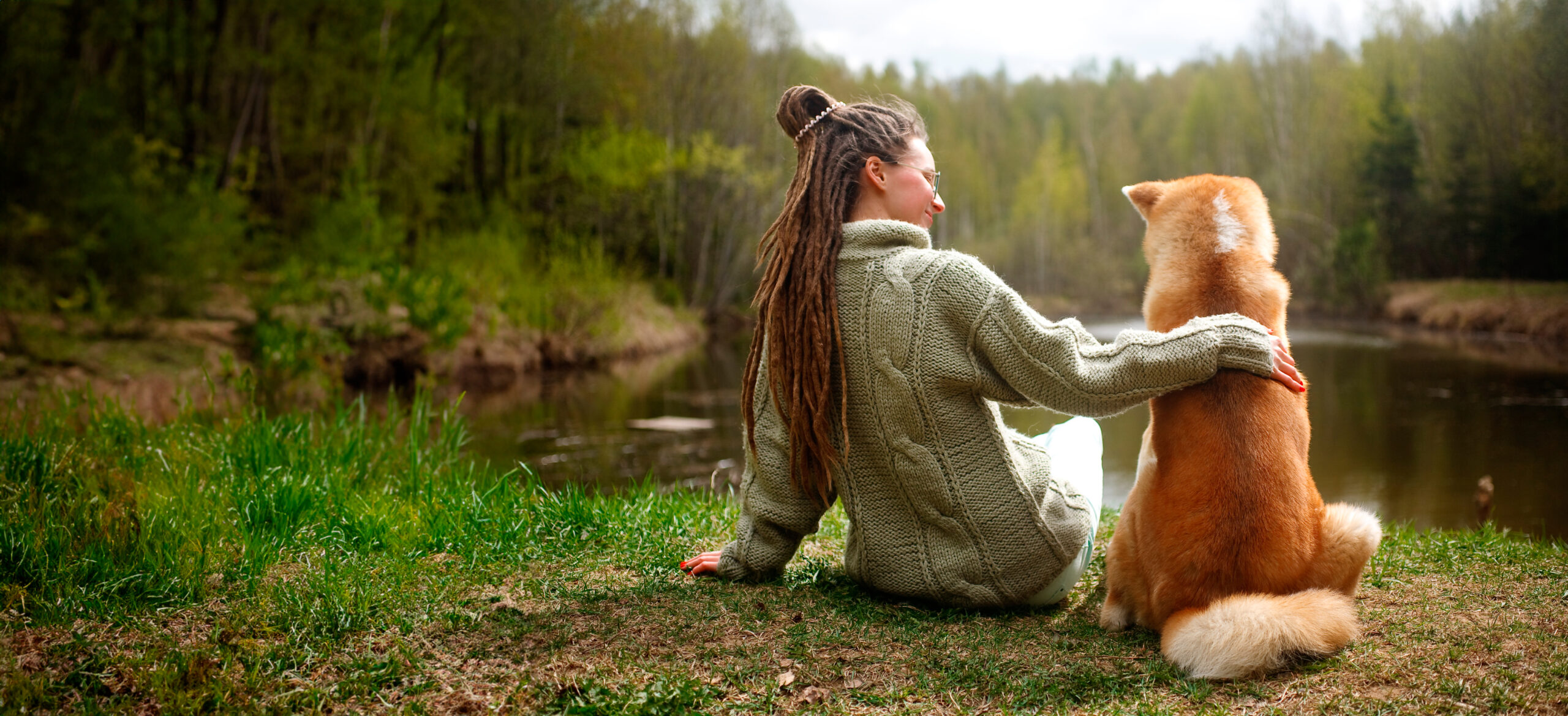 Mulher e cachorro olhando um lago