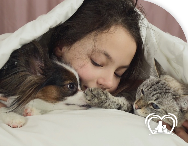Menina abraçada a um cachorro e um gato